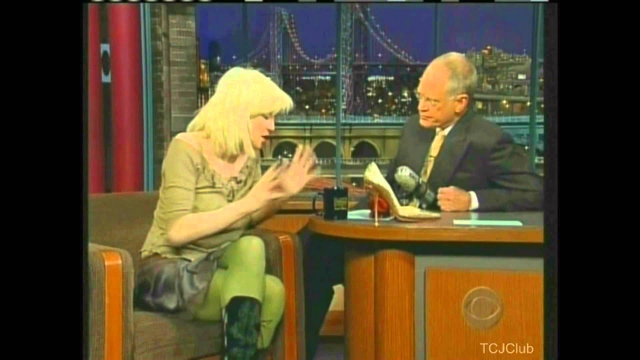 Courtney Love stands on Letterman's desk and pulls up her shirt on The Late Show